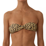 A model wearing a two-piece bikini with a tan and black leopard print. The bikini features a strapless bandeau top with a front twist detail and matching low-rise thong bottoms, shown against a plain white background.