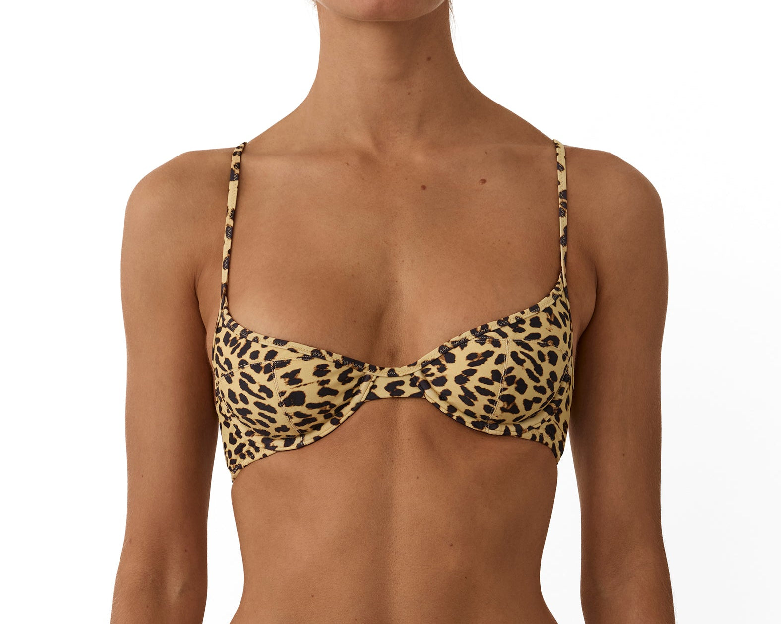 A model wearing a two-piece leopard print bikini with a tan base and black spots, shown from the neck to the upper thighs against a plain white background.